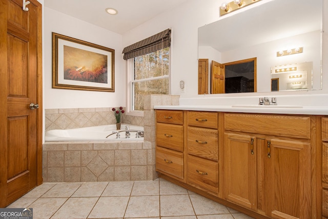 bathroom featuring tile patterned flooring, vanity, and tiled bath