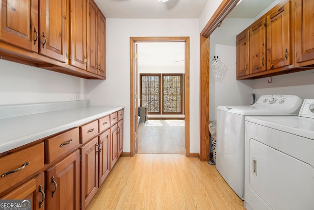 laundry room with cabinets, independent washer and dryer, and light wood-type flooring