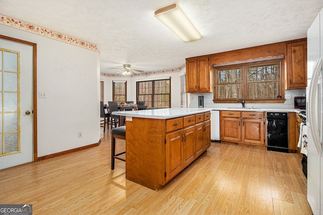 kitchen with sink, a center island, a breakfast bar area, and light hardwood / wood-style flooring