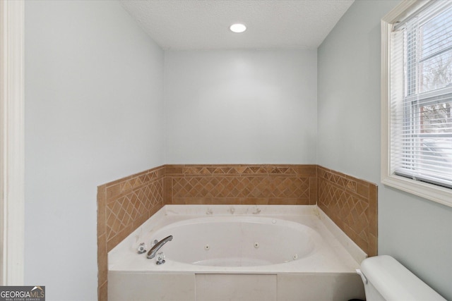 bathroom featuring a relaxing tiled tub, a textured ceiling, and toilet