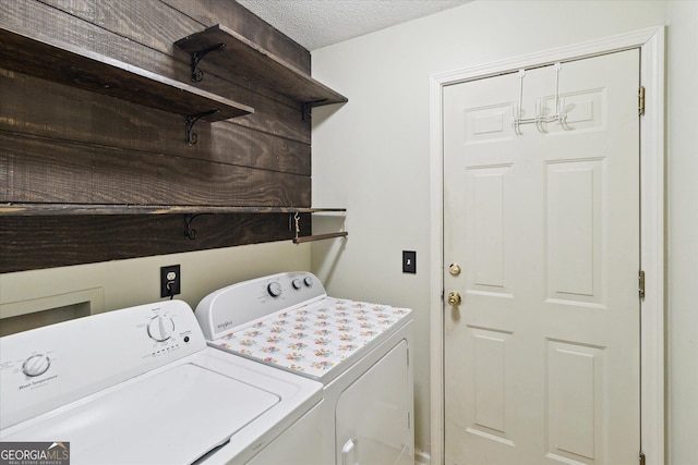 clothes washing area with independent washer and dryer and a textured ceiling