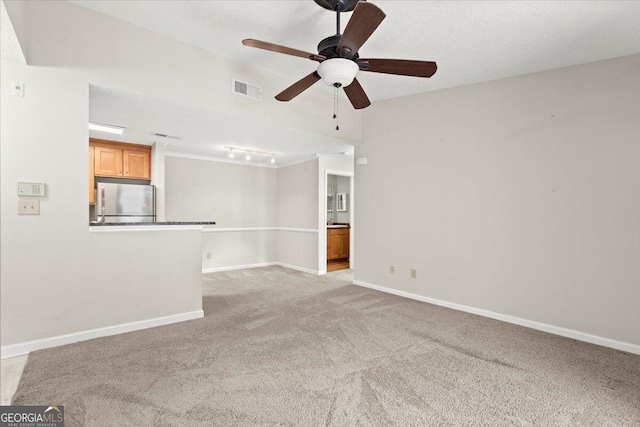 unfurnished living room featuring ceiling fan, light colored carpet, and a textured ceiling