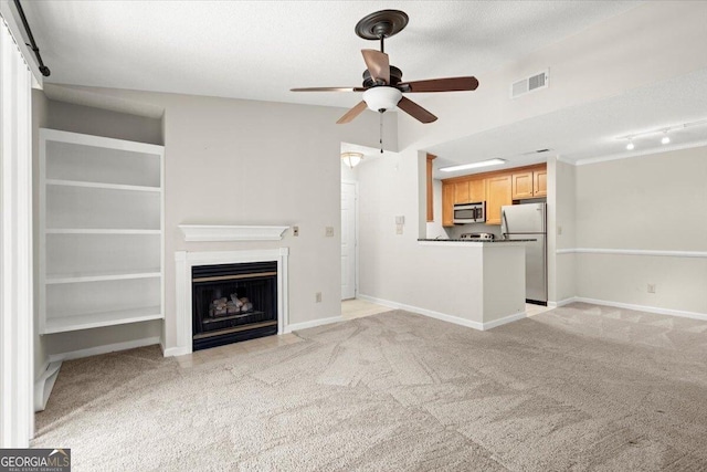 unfurnished living room with ceiling fan, light colored carpet, and a textured ceiling