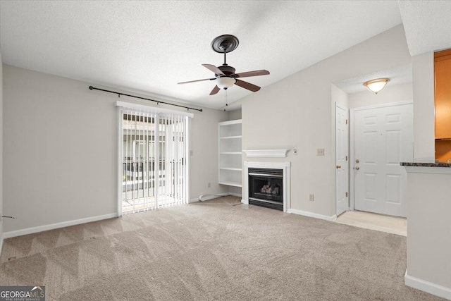 unfurnished living room with ceiling fan, light colored carpet, and a textured ceiling