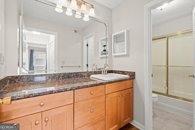 full bathroom featuring shower / bath combination with glass door, tile patterned flooring, vanity, toilet, and a textured ceiling