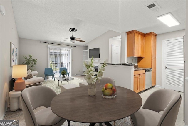 dining space with vaulted ceiling, light carpet, ceiling fan, and a textured ceiling