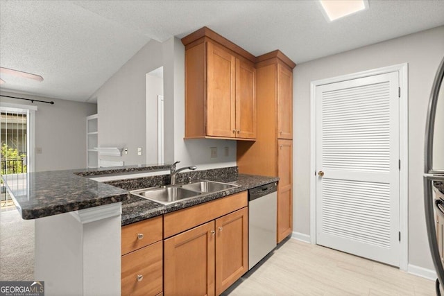 kitchen featuring sink, a textured ceiling, stainless steel dishwasher, kitchen peninsula, and dark stone counters