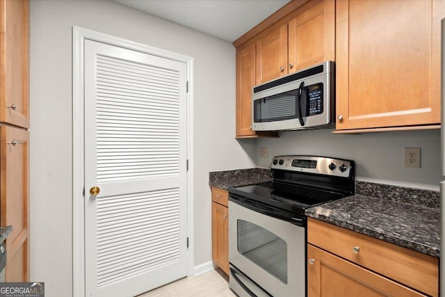 kitchen with stainless steel appliances and dark stone countertops