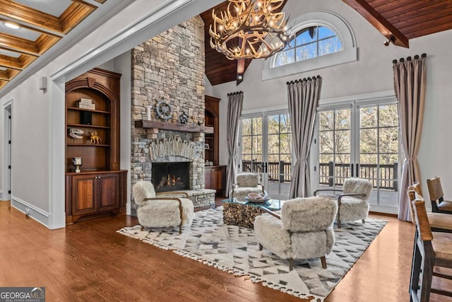 living room featuring hardwood / wood-style flooring, a stone fireplace, a wealth of natural light, and beam ceiling