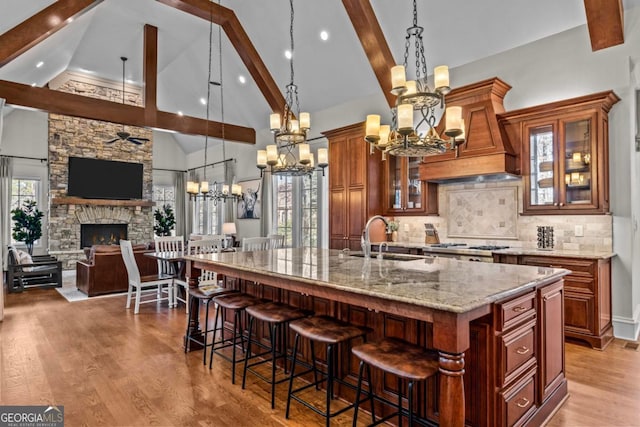 kitchen featuring light stone counters, sink, pendant lighting, and a spacious island