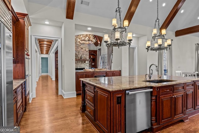 kitchen featuring sink, light hardwood / wood-style flooring, stainless steel dishwasher, an island with sink, and pendant lighting