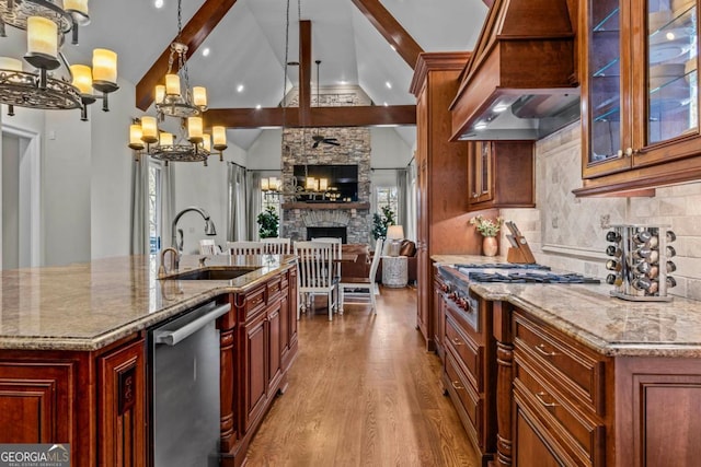 kitchen featuring decorative light fixtures, light stone countertops, sink, and a center island with sink