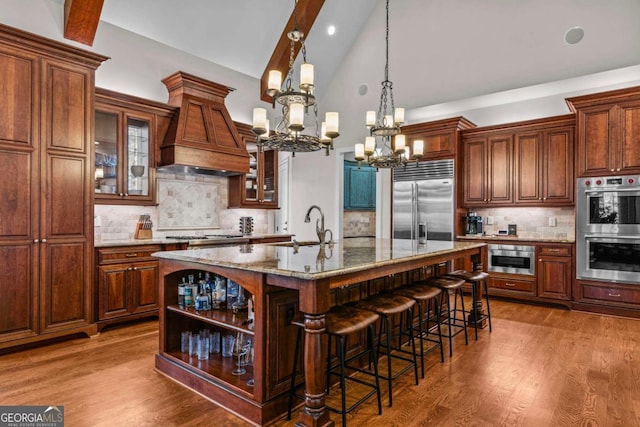 kitchen featuring light stone counters, a center island with sink, dark hardwood / wood-style floors, and appliances with stainless steel finishes