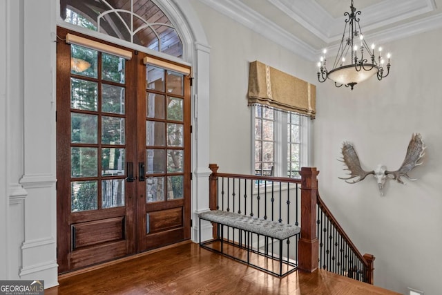 foyer featuring crown molding, hardwood / wood-style floors, a tray ceiling, french doors, and a chandelier