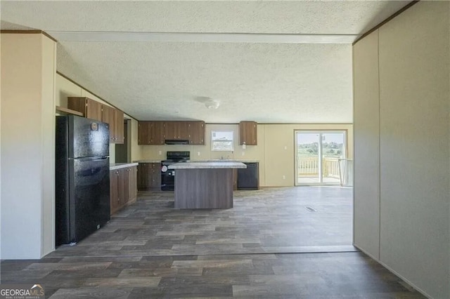 kitchen with dark wood-style floors, a center island, light countertops, a textured ceiling, and black appliances