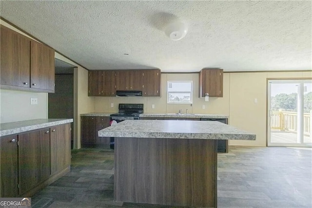 kitchen with a center island, light countertops, under cabinet range hood, and black appliances