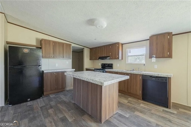 kitchen featuring dark wood-type flooring, light countertops, under cabinet range hood, and black appliances