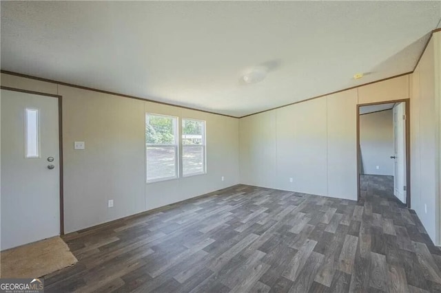 spare room featuring ornamental molding and dark wood finished floors