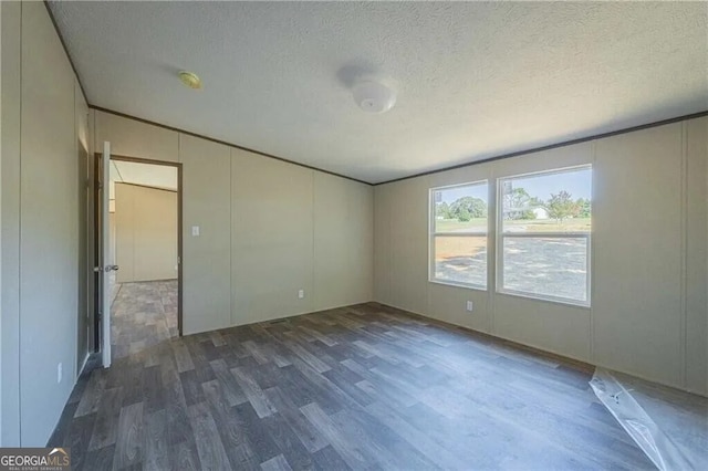 spare room featuring dark wood-style floors, crown molding, and a textured ceiling