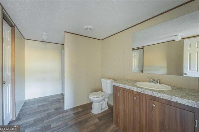 bathroom with toilet, a textured ceiling, vanity, and wood finished floors