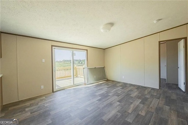 spare room featuring a textured ceiling, dark wood-type flooring, and crown molding