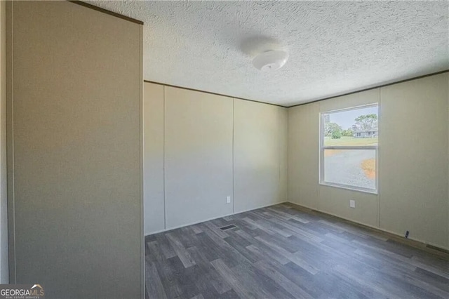 spare room featuring dark wood finished floors and a textured ceiling