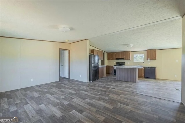 kitchen with a kitchen island, brown cabinets, open floor plan, light countertops, and black appliances