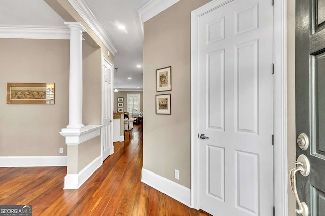 corridor featuring wood-type flooring, ornamental molding, and ornate columns