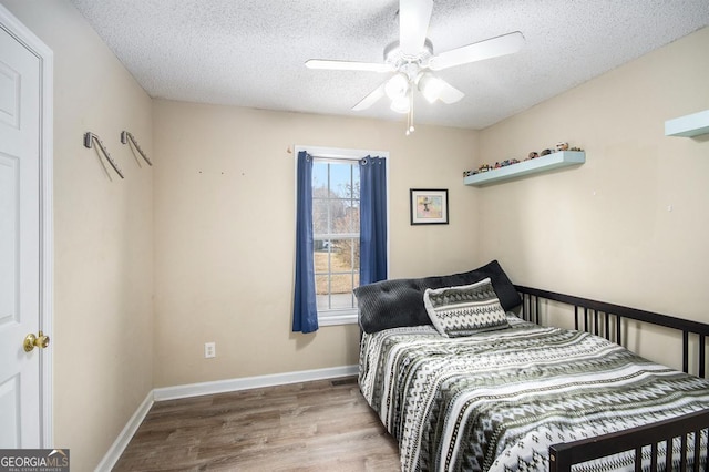 bedroom with hardwood / wood-style floors, a textured ceiling, and ceiling fan