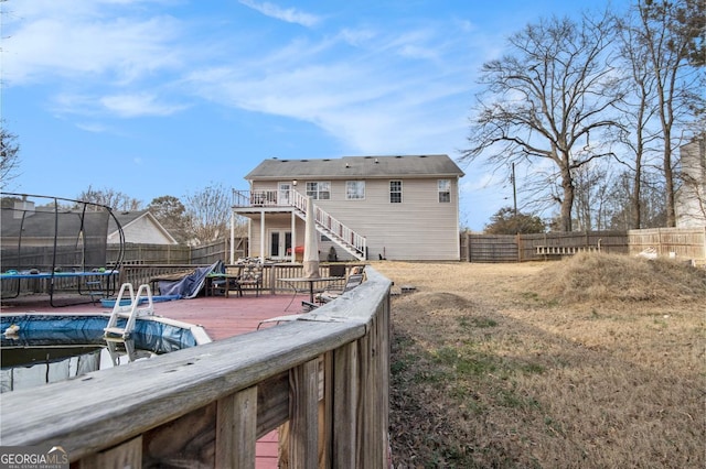 rear view of property with a wooden deck and a trampoline