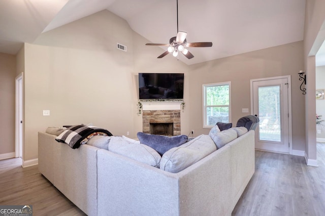 living room featuring ceiling fan, high vaulted ceiling, a fireplace, and light wood-type flooring