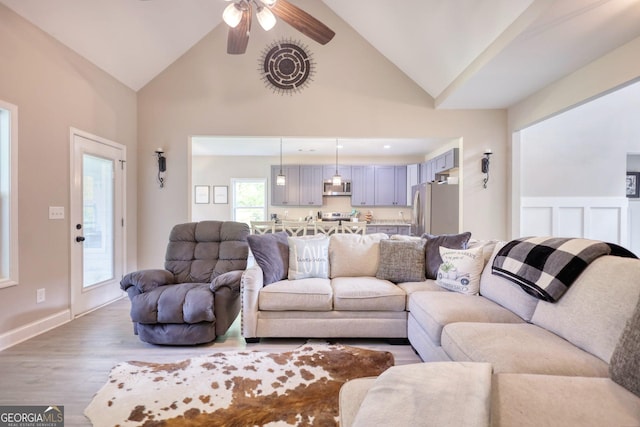 living room with hardwood / wood-style flooring, high vaulted ceiling, and ceiling fan