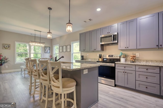 kitchen featuring light stone countertops, stainless steel appliances, and a center island