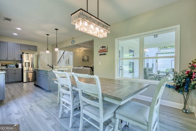 dining room featuring an inviting chandelier, sink, and light hardwood / wood-style floors