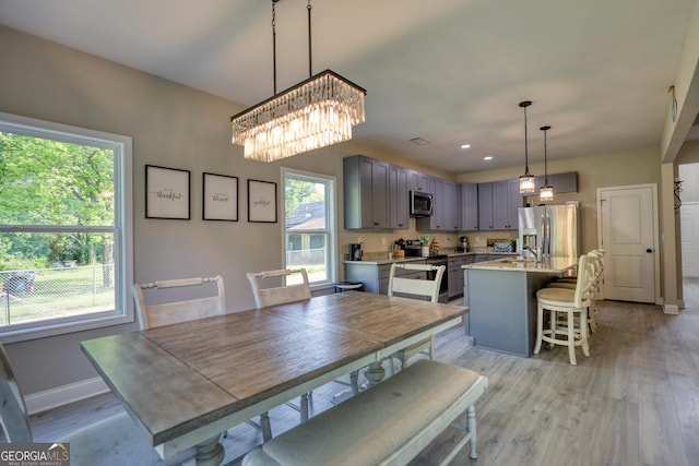 dining area with a chandelier, sink, and light hardwood / wood-style flooring