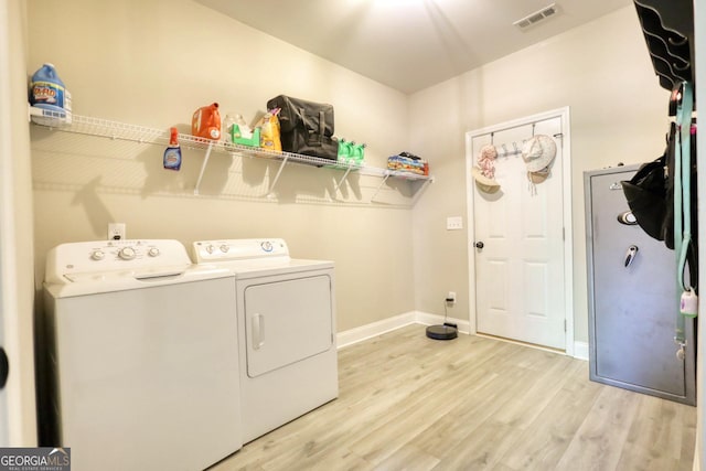 laundry area with washer and dryer and light wood-type flooring