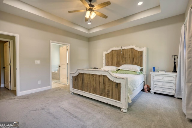 carpeted bedroom with ensuite bath, a raised ceiling, and ceiling fan