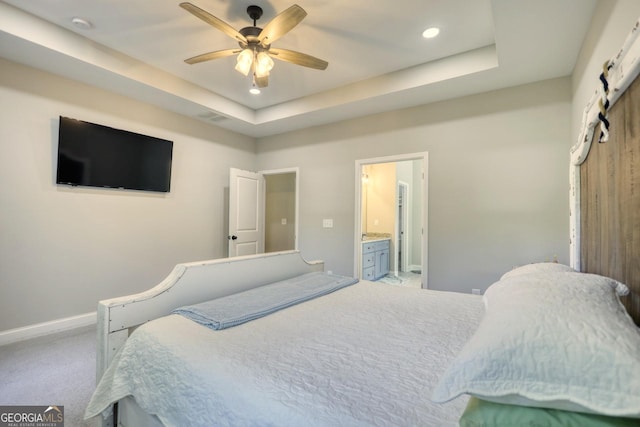 carpeted bedroom with ceiling fan, ensuite bathroom, and a tray ceiling