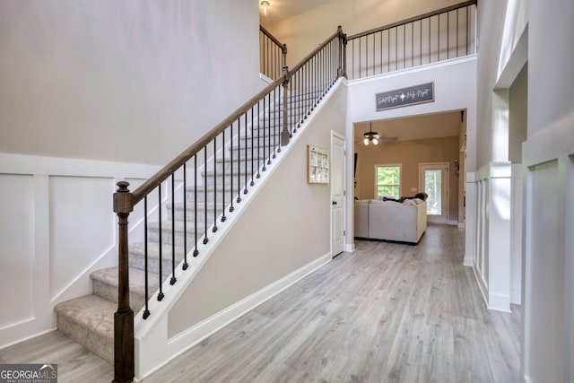 stairs with hardwood / wood-style floors and a towering ceiling