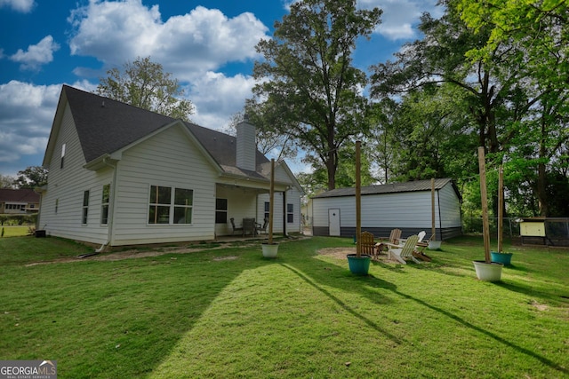 rear view of house with an outdoor fire pit and a lawn