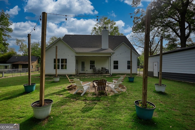 rear view of house with a lawn and a fire pit