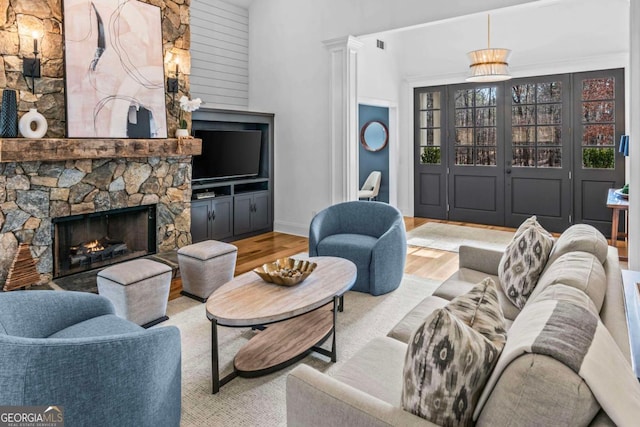 living room with a high ceiling, a fireplace, and light hardwood / wood-style floors