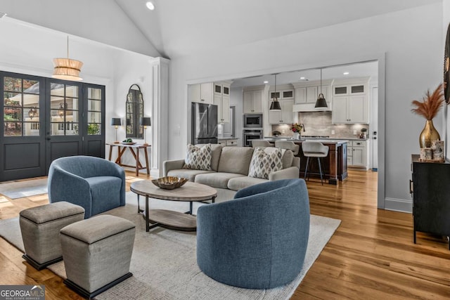 living room with light hardwood / wood-style flooring and high vaulted ceiling