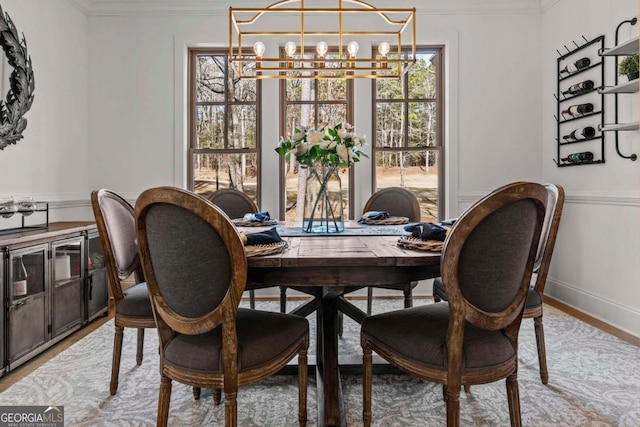 dining space with crown molding, hardwood / wood-style floors, and a notable chandelier