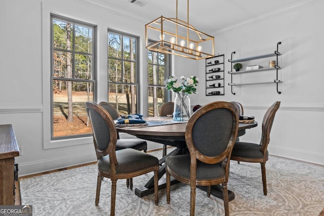 dining room with crown molding, a chandelier, and light hardwood / wood-style flooring