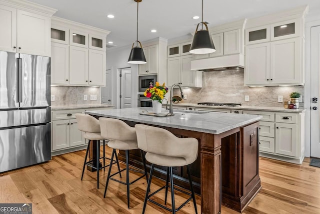 kitchen featuring hanging light fixtures, an island with sink, appliances with stainless steel finishes, and white cabinetry