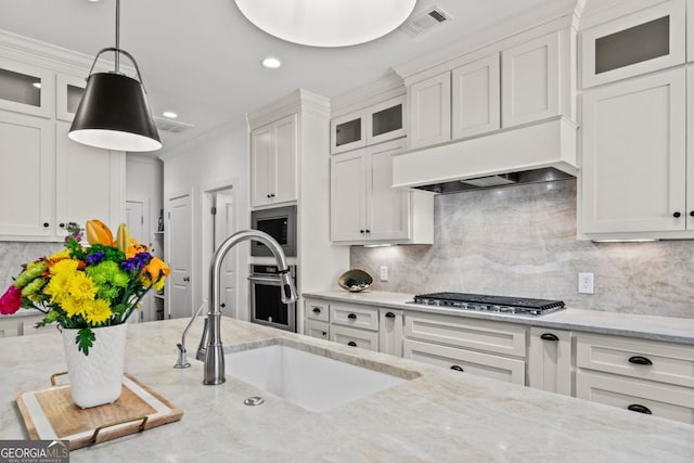 kitchen featuring hanging light fixtures, white cabinetry, stainless steel gas cooktop, and light stone counters