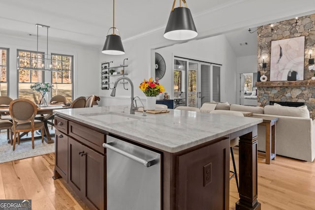 kitchen featuring light stone counters, sink, decorative light fixtures, and stainless steel dishwasher