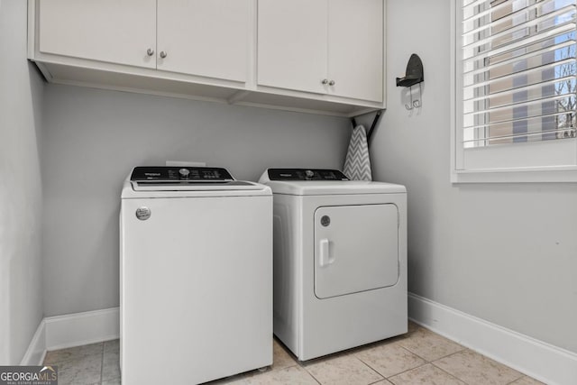 clothes washing area with cabinets, separate washer and dryer, and light tile patterned floors