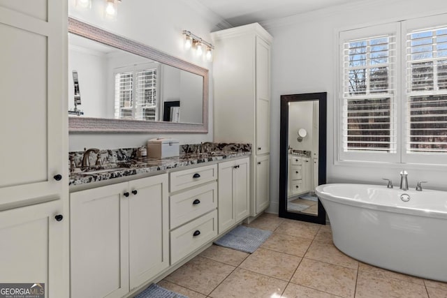 bathroom with tile patterned floors, ornamental molding, a bathing tub, and vanity